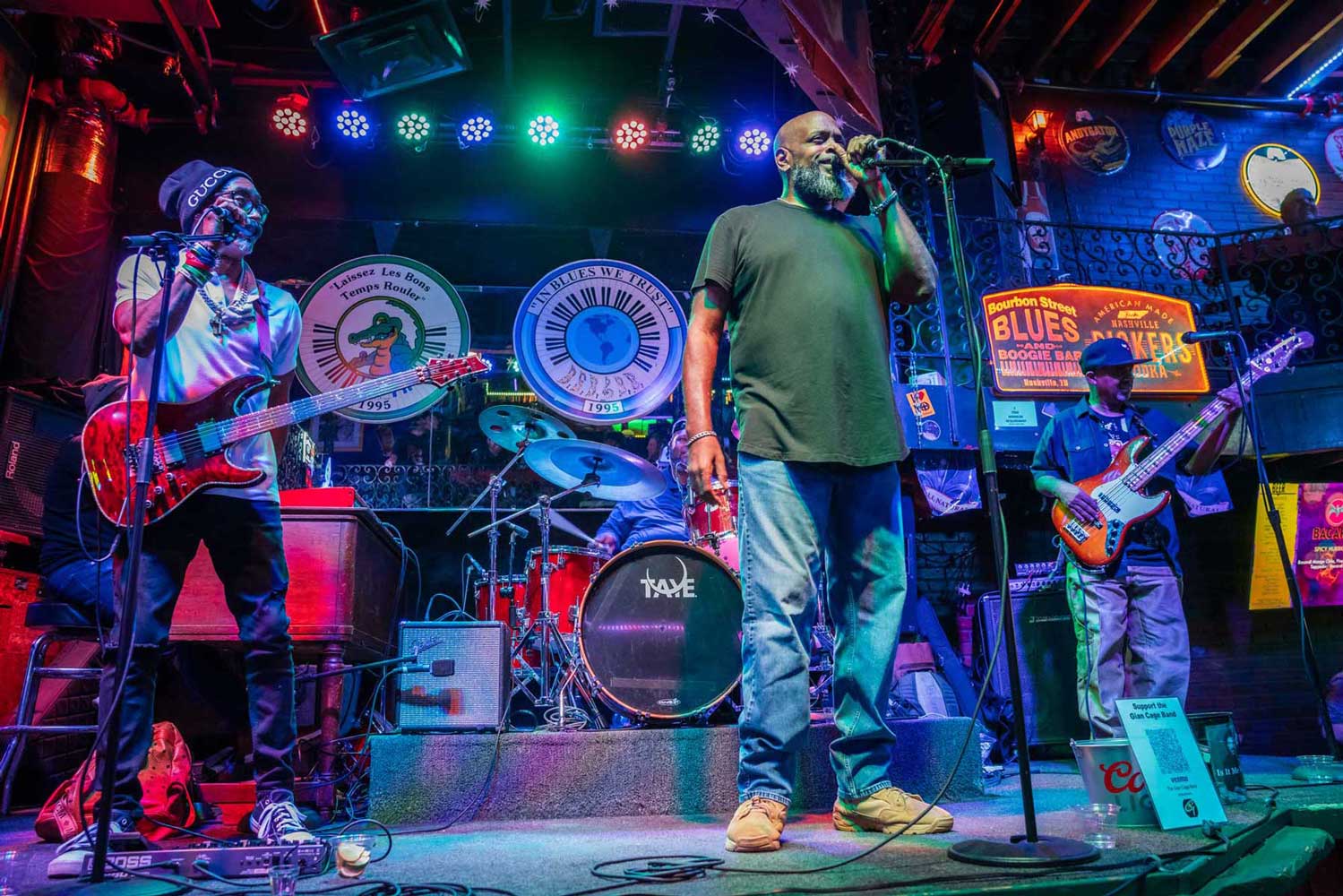 A band with three Black men performing live music on a brightly lit stage, symbolizing the constitutional freedom of cultural and artistic expression.